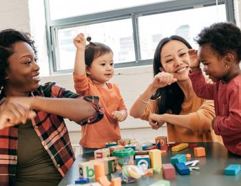 Two pre-school teachers interacting with students.