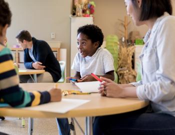 Smiling elementary student interacting with teachers and students. 