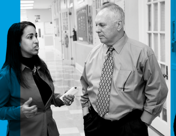 Teacher and student talking in a school hallway.