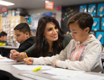 Teacher assisting an elementary student with an assignment