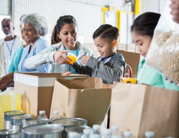 Adults and children bagging food donations.