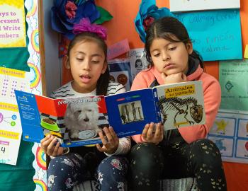 Two elementary students reading a book together.