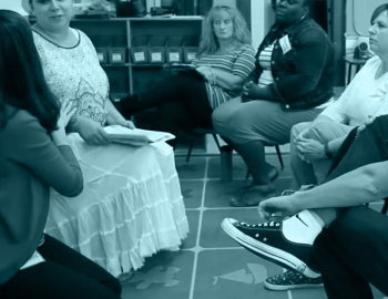 A group of adults seated in a circle having a discussion.