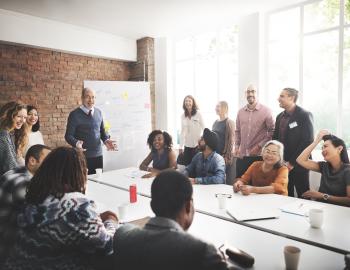 Group of adults listening to a presentation around a conference table.