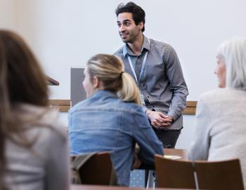 An educator speaking in front of a classroom with adults.