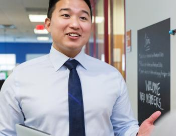 Teacher speaking with a colleague in a school hallway.