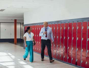 Two educators walking in a school hallway.
