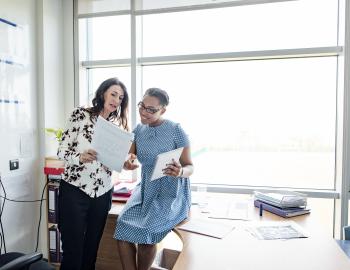 Two educators talking in a classroom.