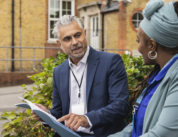 Two educators having a discussion outside of a school.