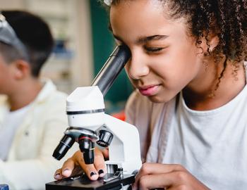 Middle school student looking through a microscope.