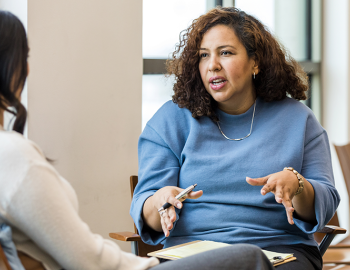 Two adults having a discussion in a classroom.