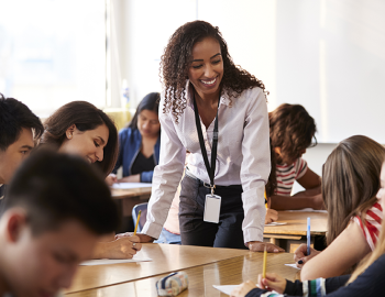 A teacher interacting with middle school students in a classroom.