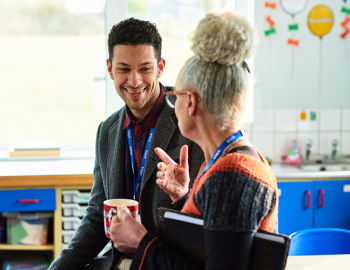 Two educators having a discussion in a classroom.