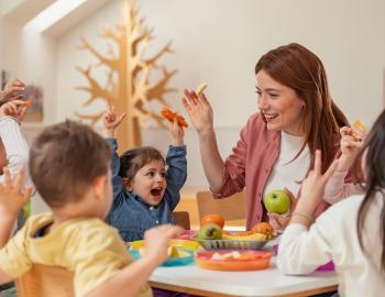 A teacher playing with elementary school students at a table.